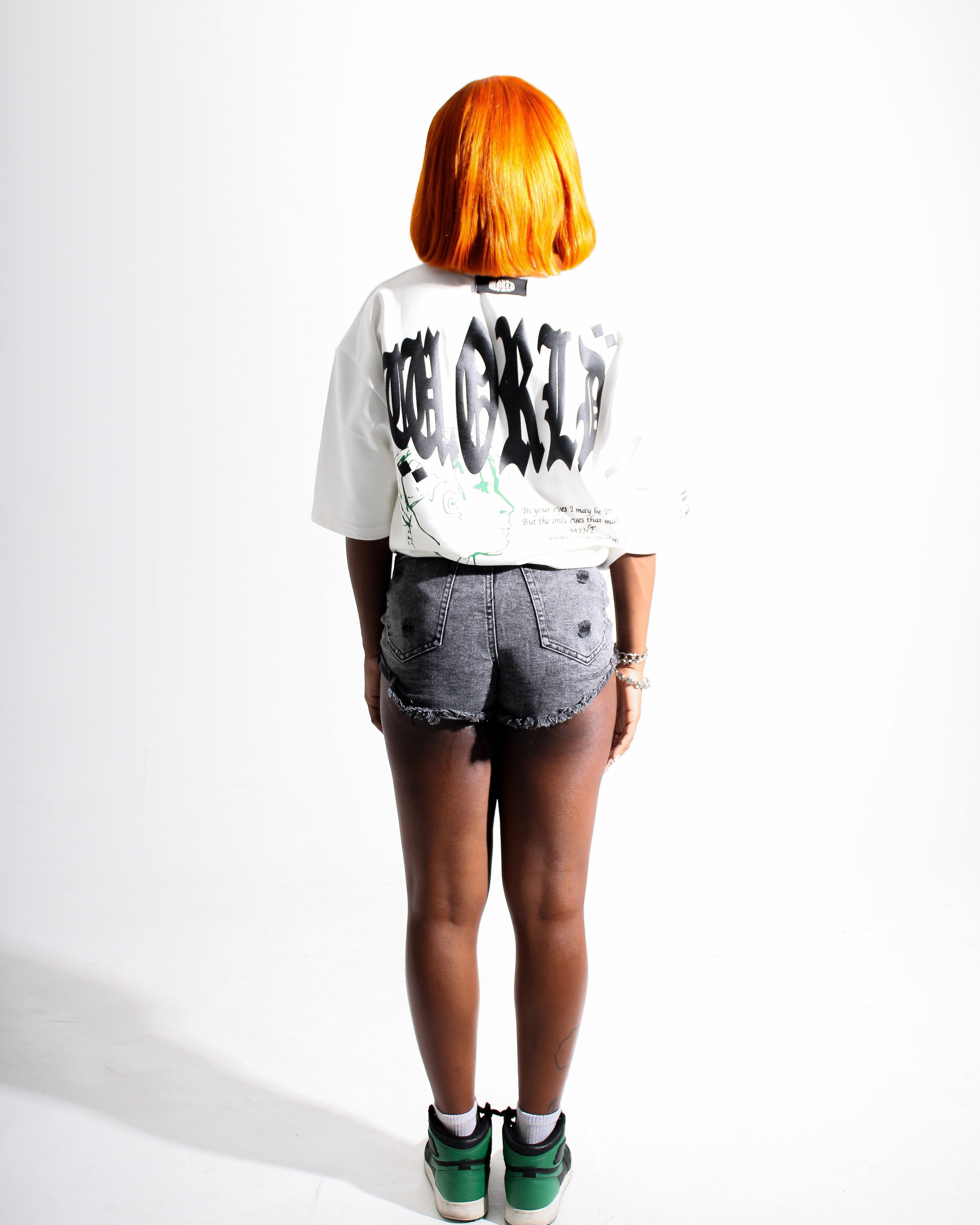 Person wearing a white crop top with black text and denim shorts on a white background