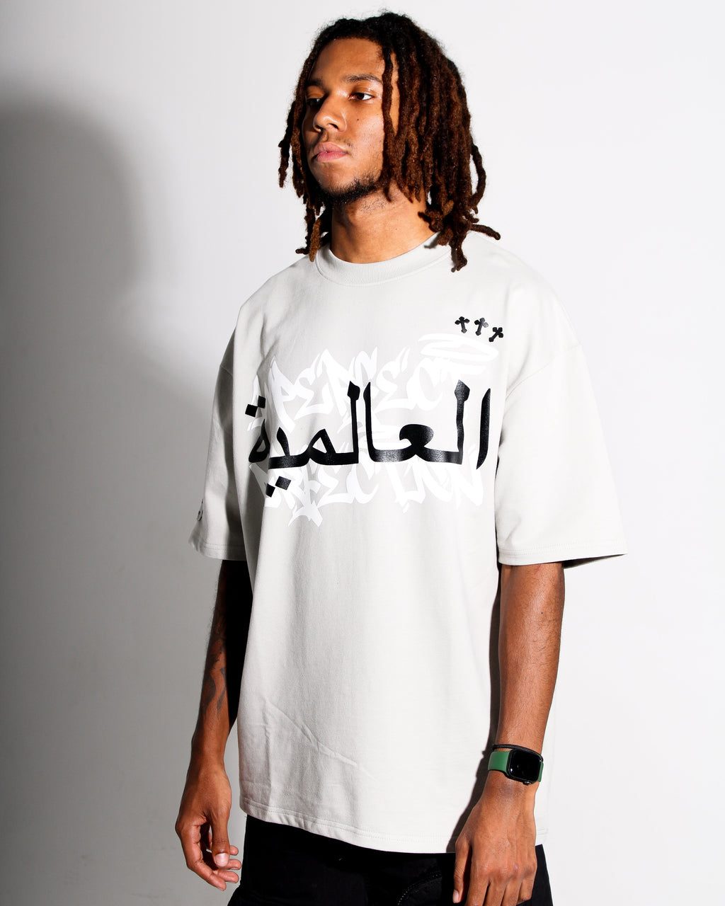 Person wearing a grey t-shirt with Arabic text on a plain background