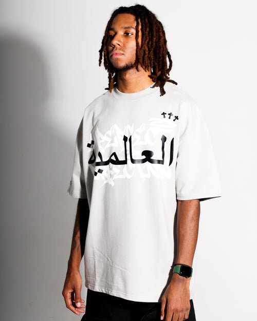 Person wearing a grey t-shirt with Arabic text on a plain background
