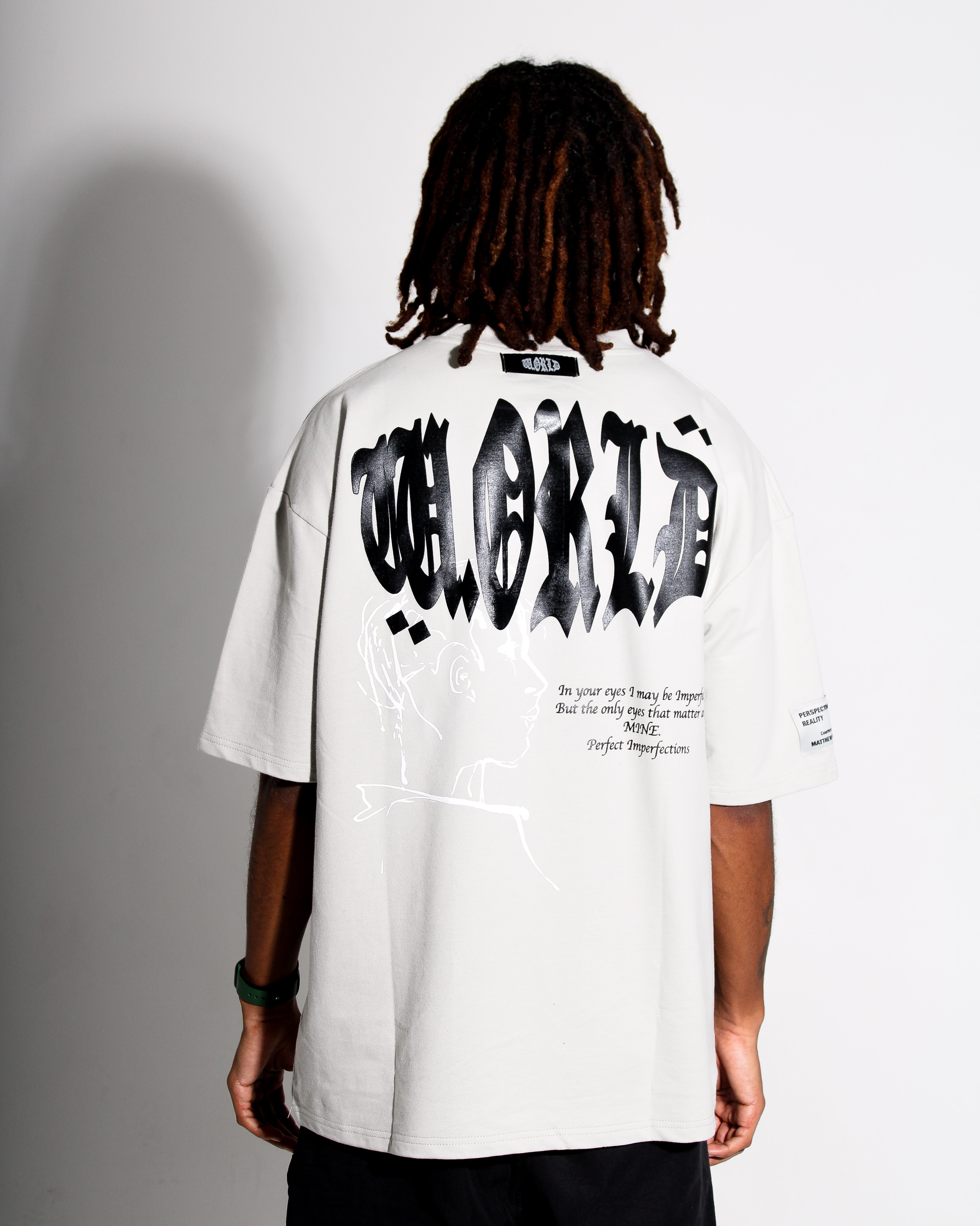 Person wearing a grey t-shirt with black text on the back against a gray background