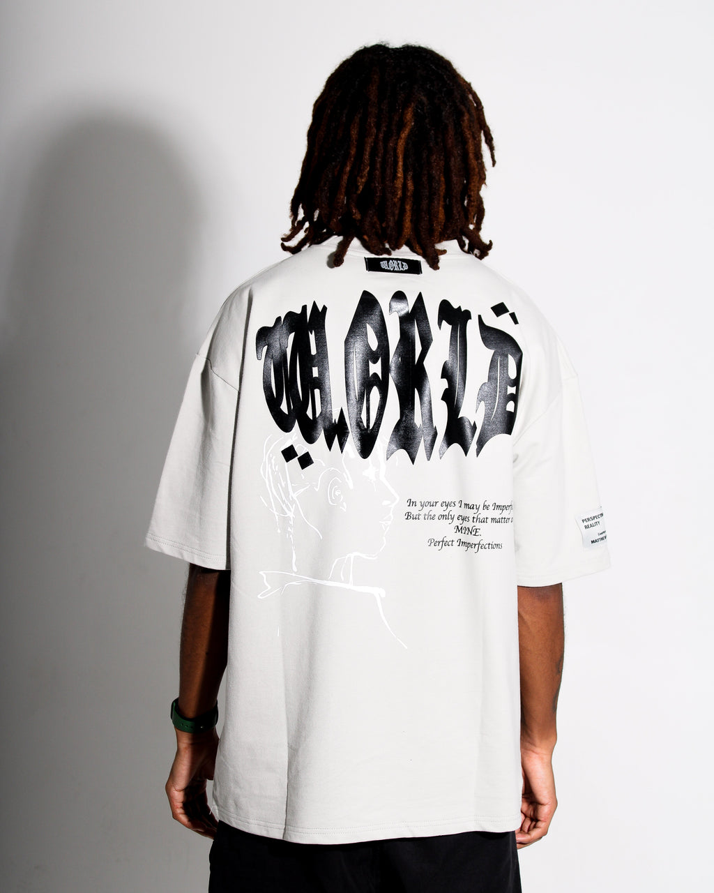 Person wearing a grey t-shirt with black text on the back against a gray background