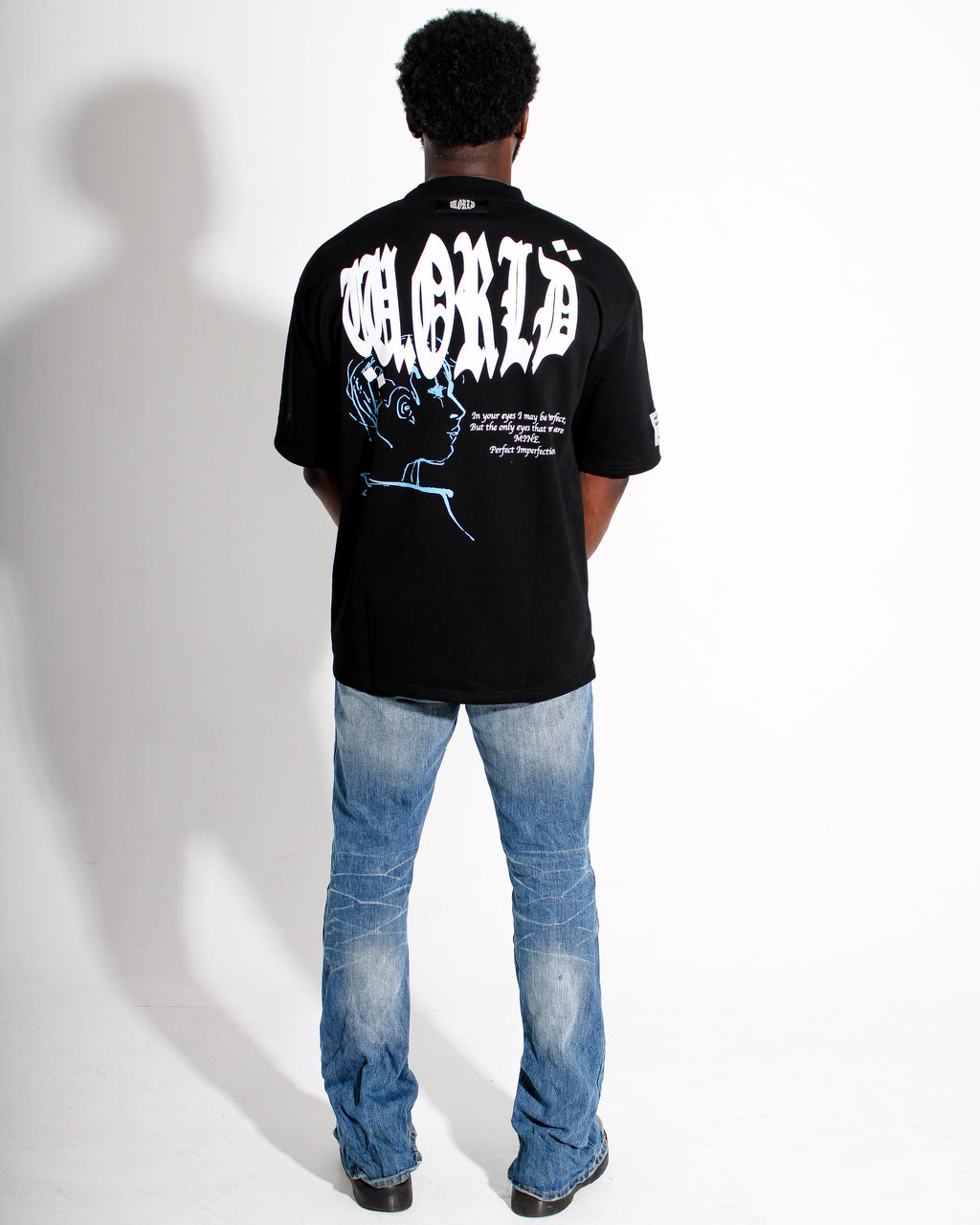 Person wearing a black t-shirt with white text and graphics on the back, standing against a white background.