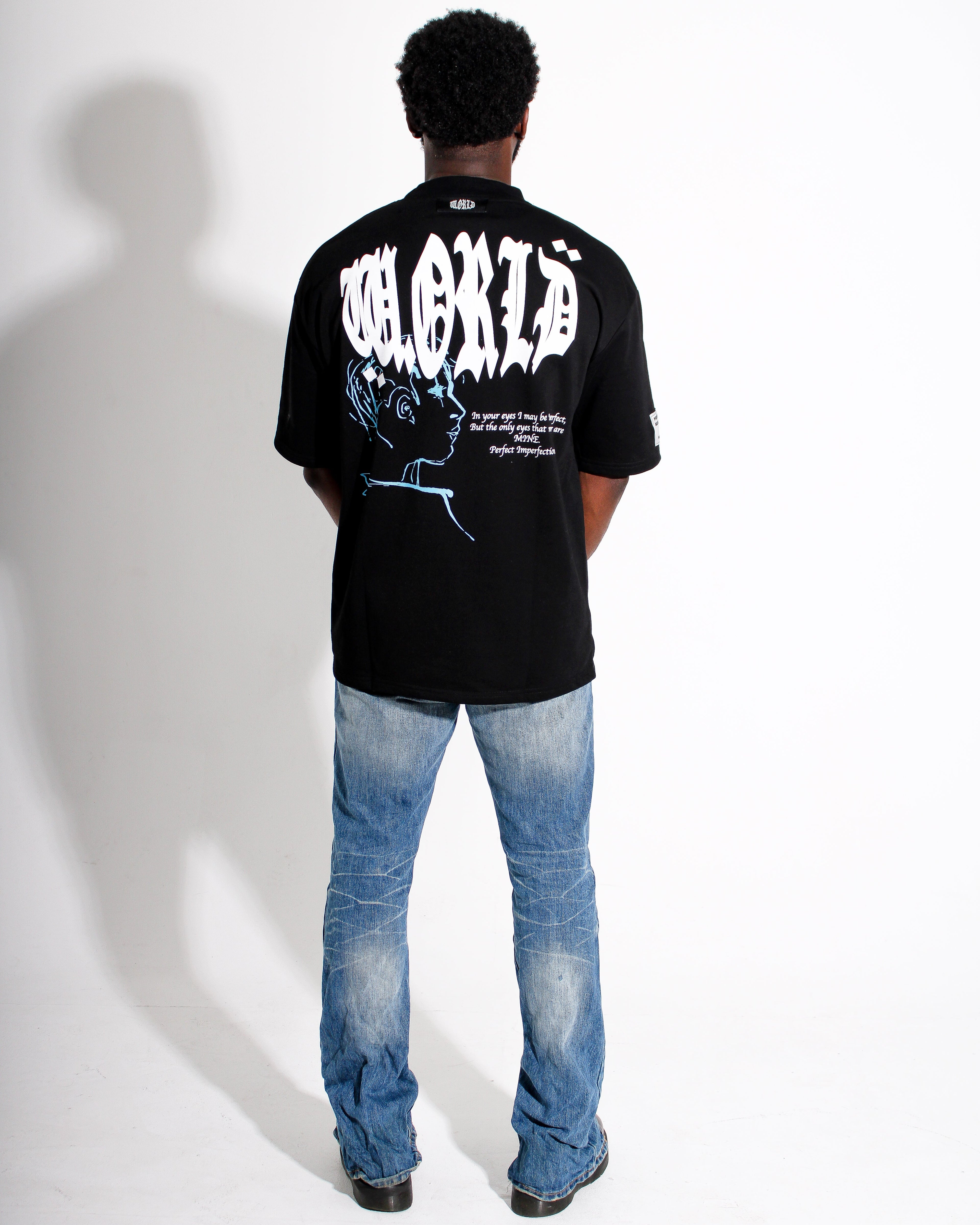 Person wearing a black t-shirt with white text and graphics on the back, standing against a white background.