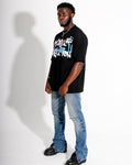 Man wearing a black t-shirt with graphic design and blue jeans on a white background