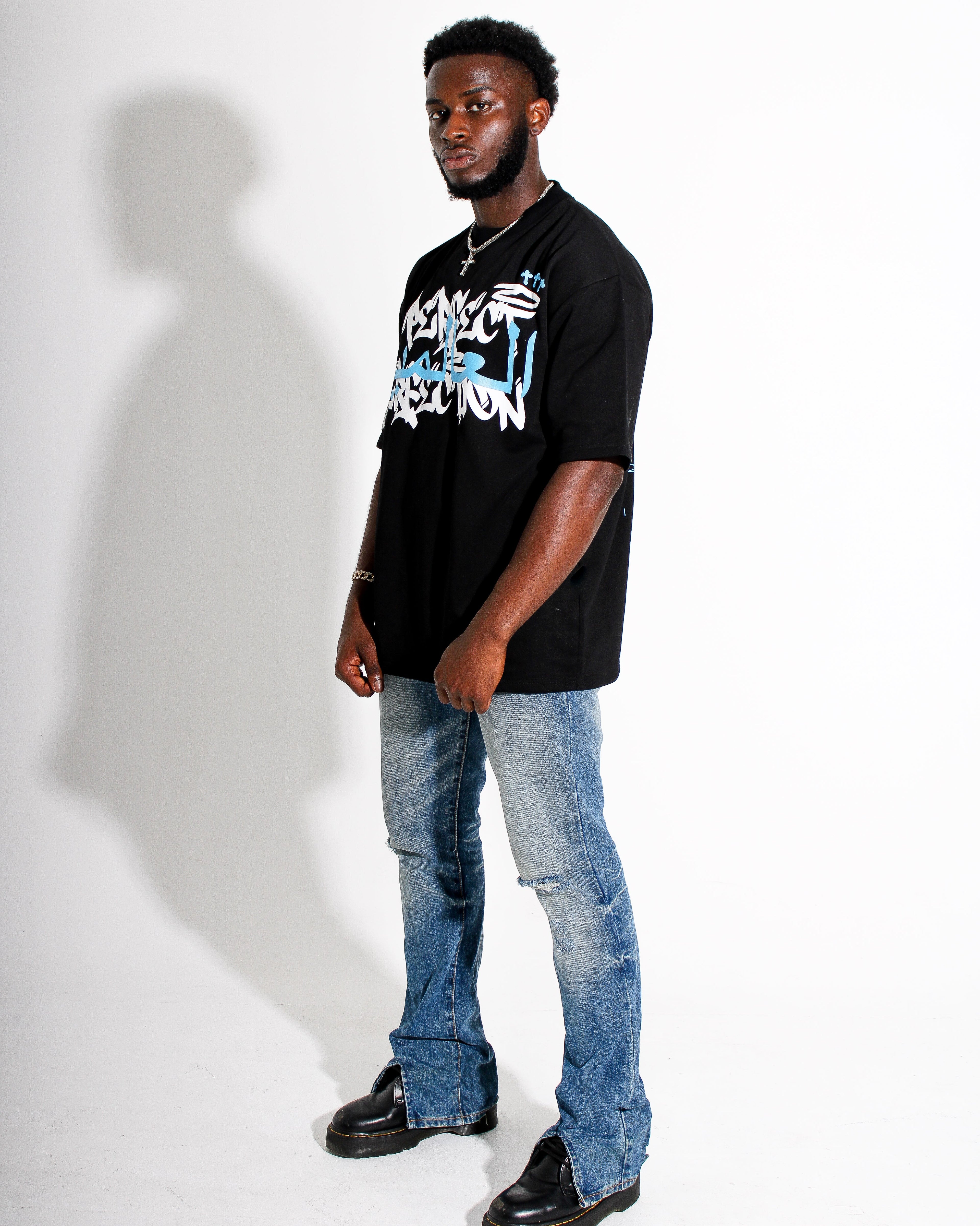 Man wearing a black t-shirt with graphic design and blue jeans on a white background