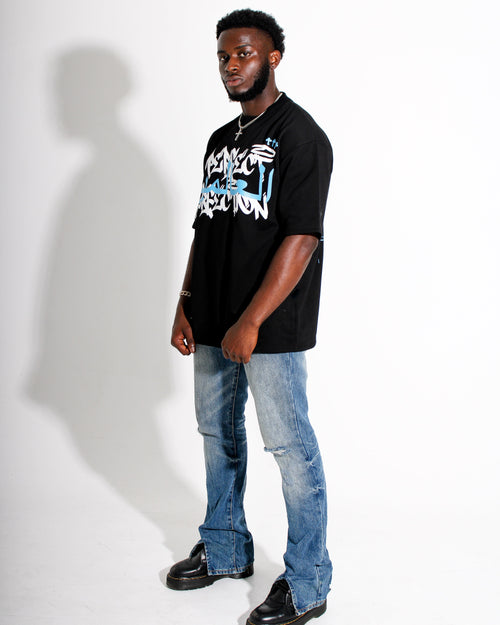 Man wearing a black t-shirt with graphic design and blue jeans on a white background