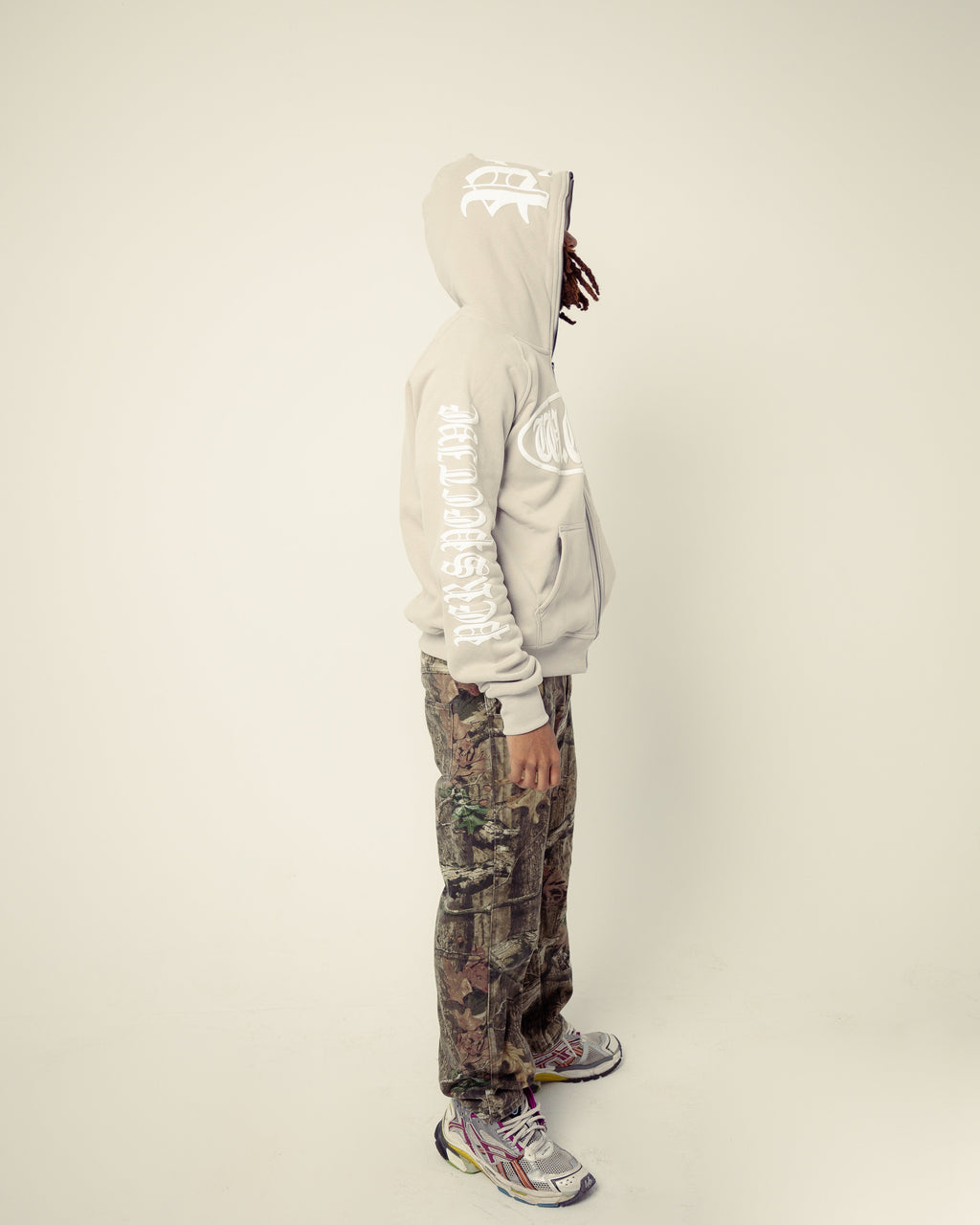 Person wearing a reflective hoodie and camouflage pants on a plain background