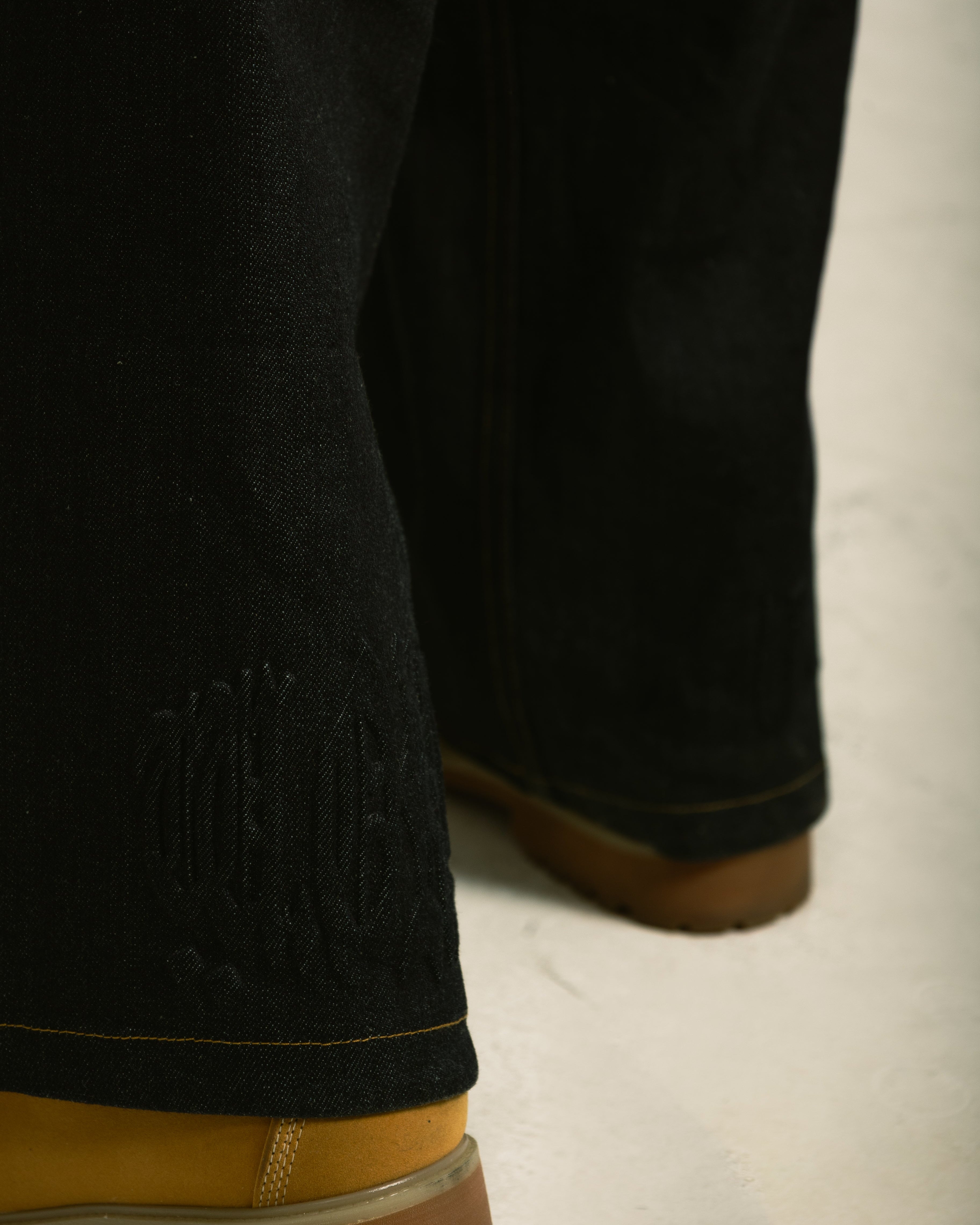 Close-up of black pants and brown boots on a light background