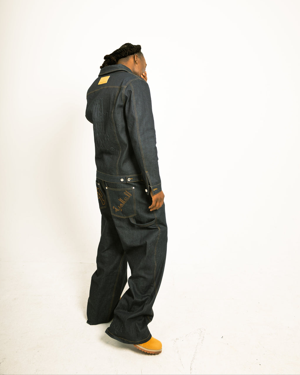 Person wearing a dark denim jumpsuit on a white background