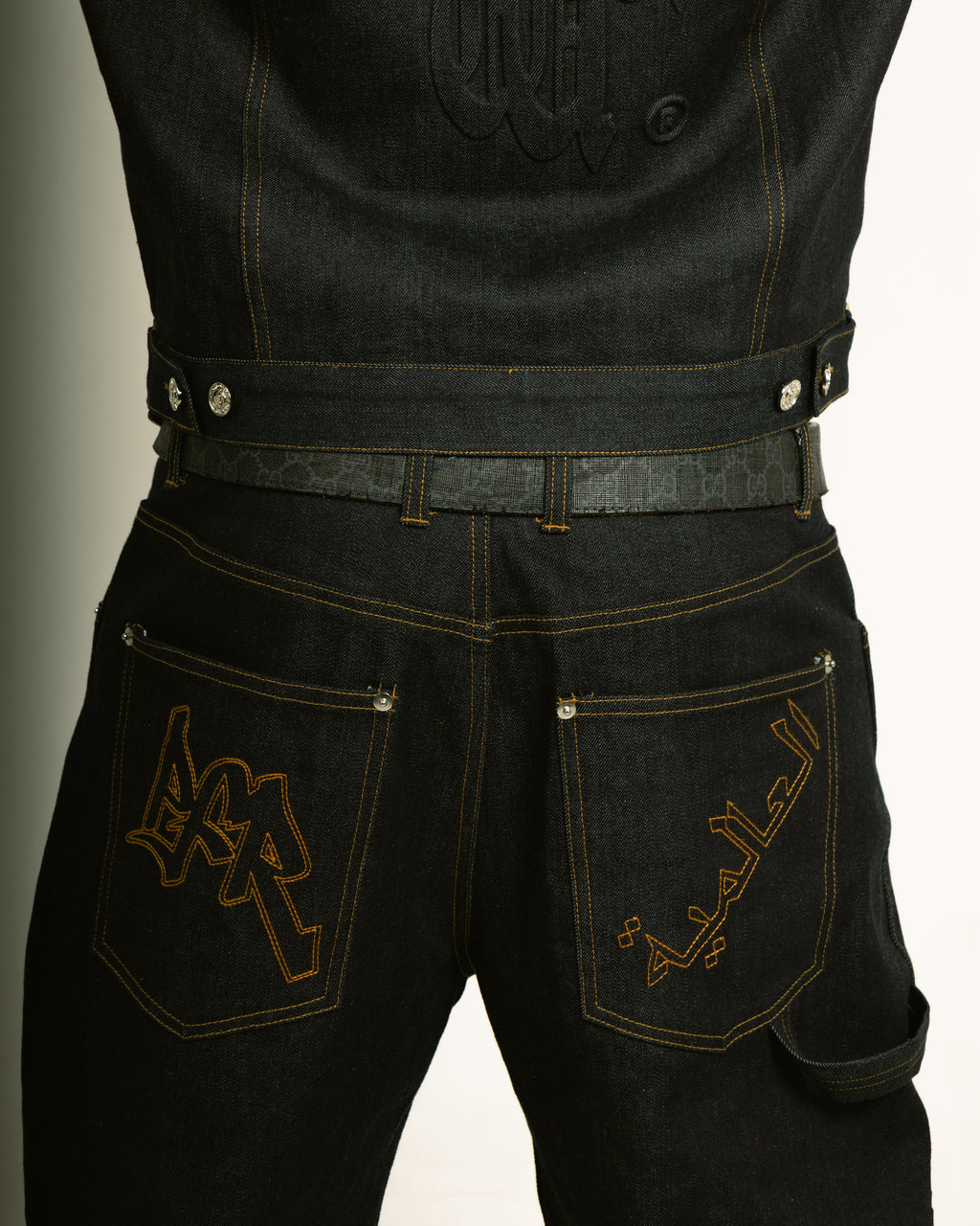 Black jeans with gold embroidery on a neutral background