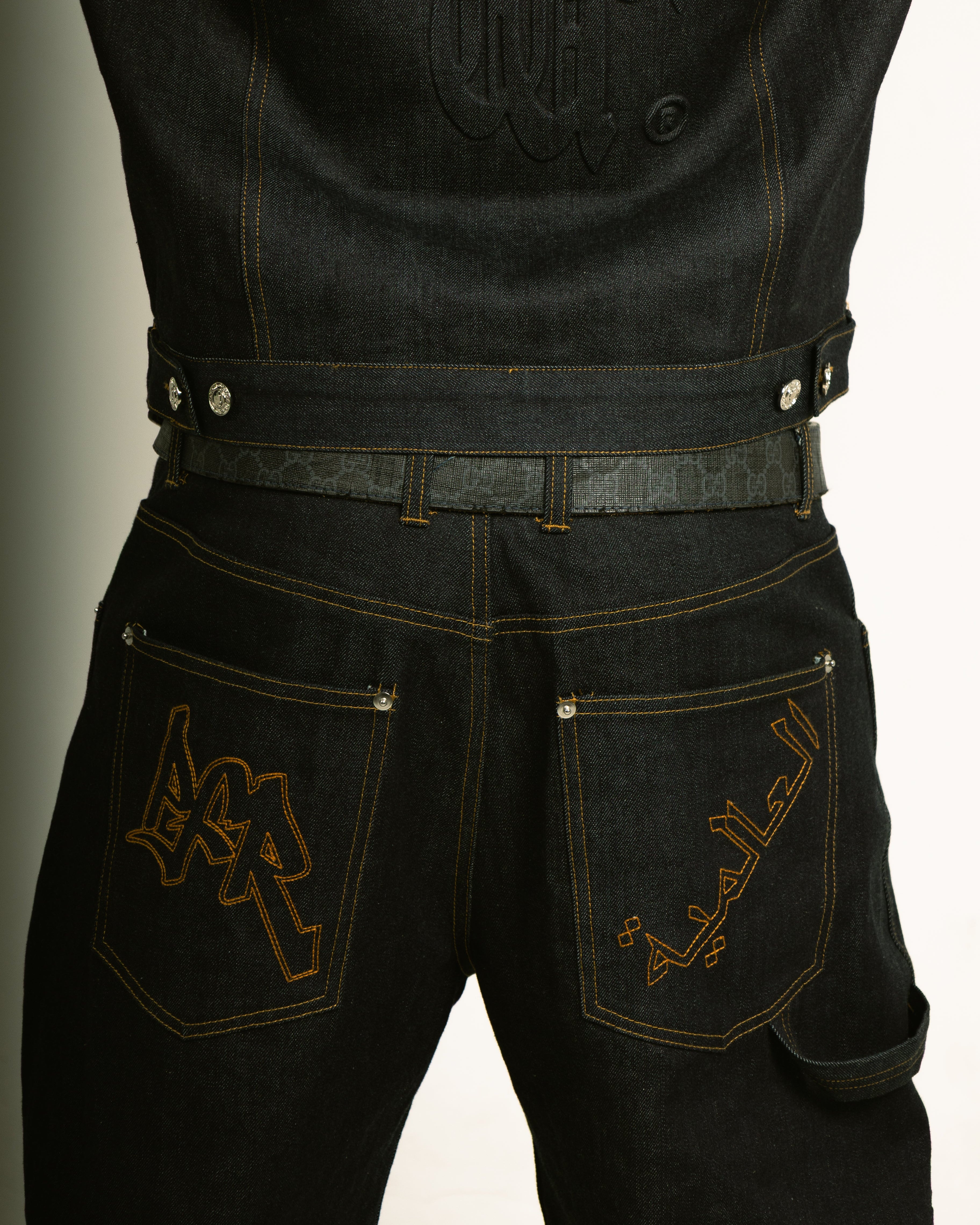 Black jeans with gold embroidery on a neutral background