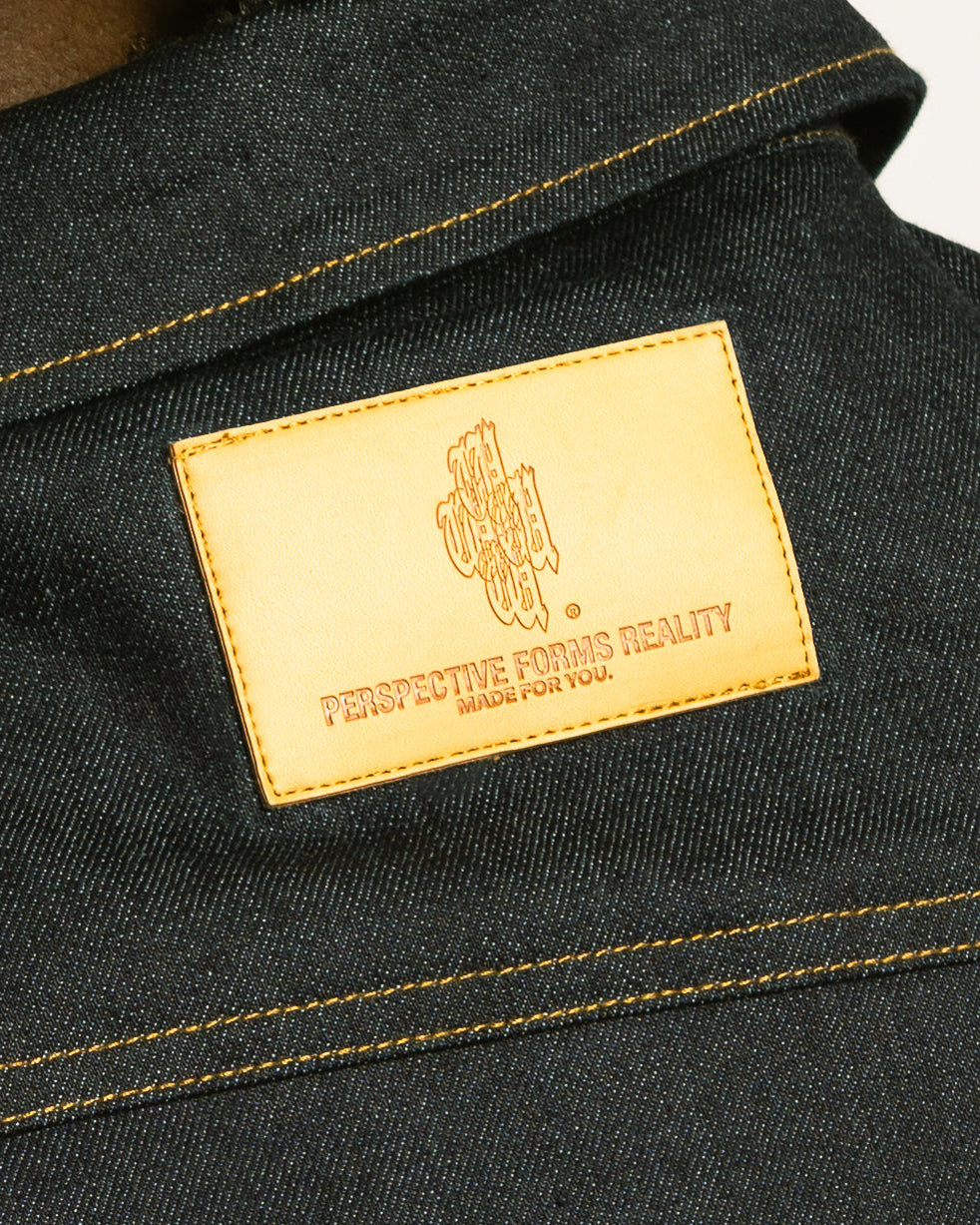 Close-up of a dark denim fabric with a gold label featuring text and a logo.