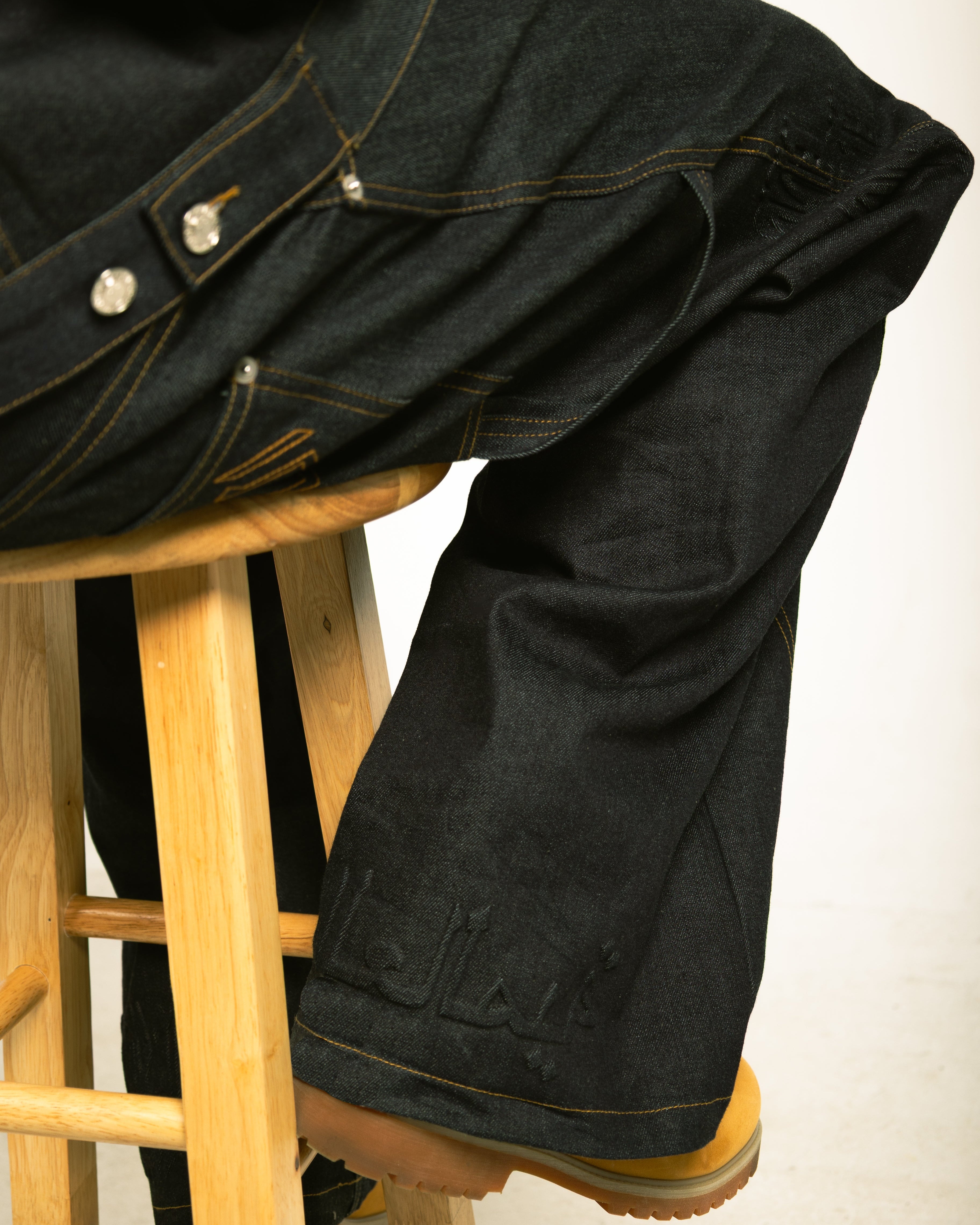Black jacket and pants on a wooden stool against a white background